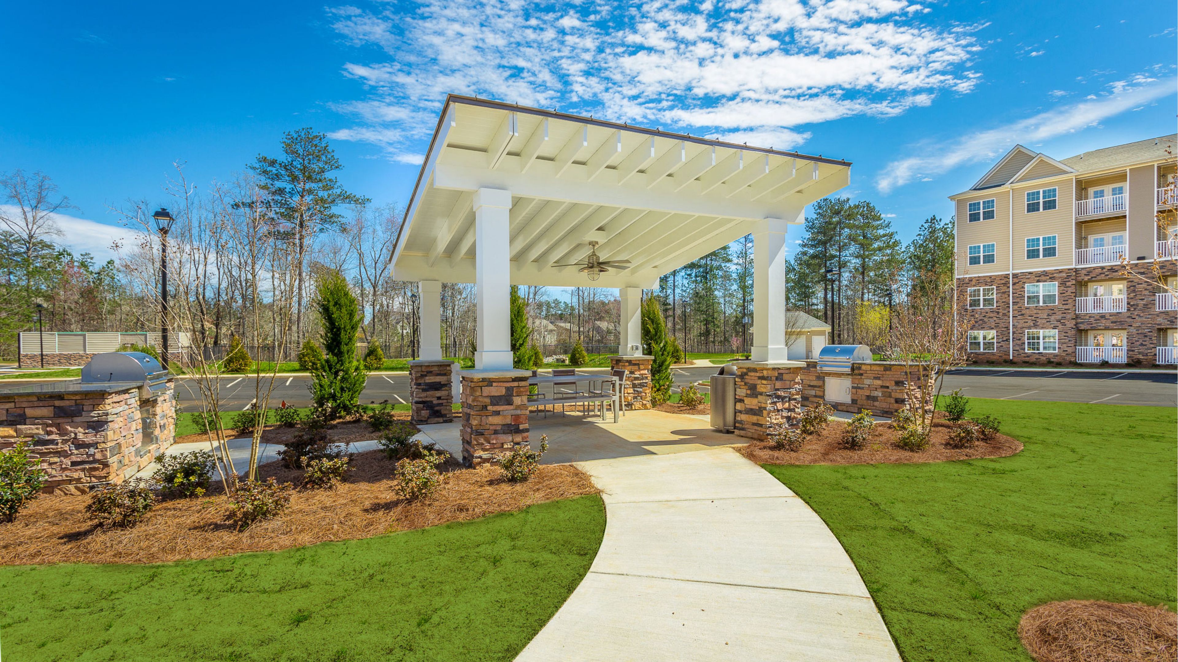 Hawthorne at Mirror Lake apartments community exterior with large green lawn and outdoor picnic and BBQ area